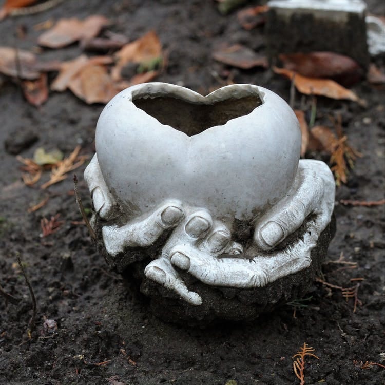 Hands cradling a clay heart sculpture