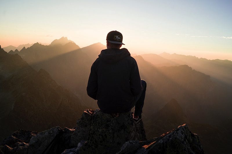 A person reflecting on life at a mountain edge