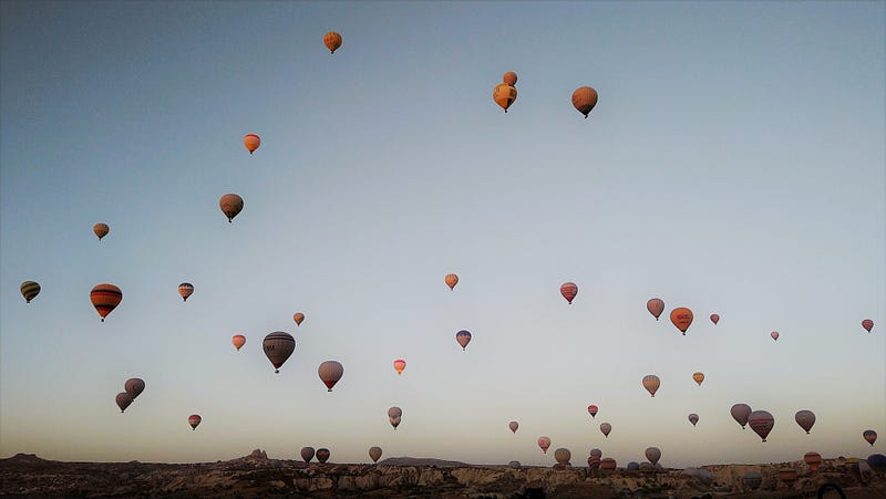 Hot air balloons rising over Cappadocia at dawn.